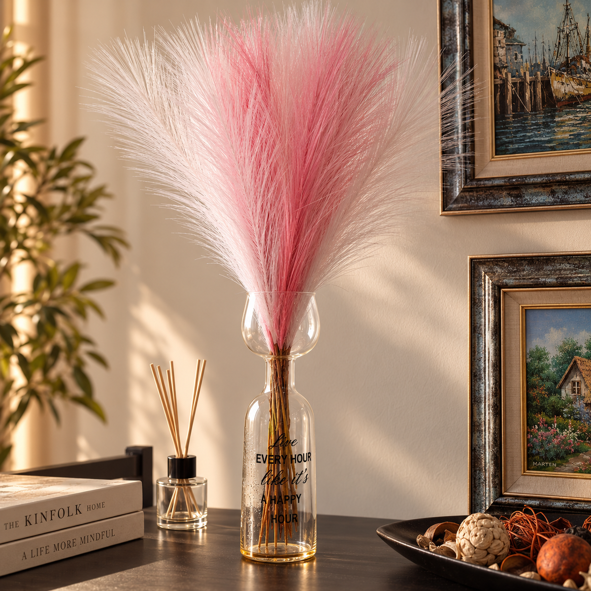 Pink and white fluffy pampas-style decorative stems arranged in a tall glass vase