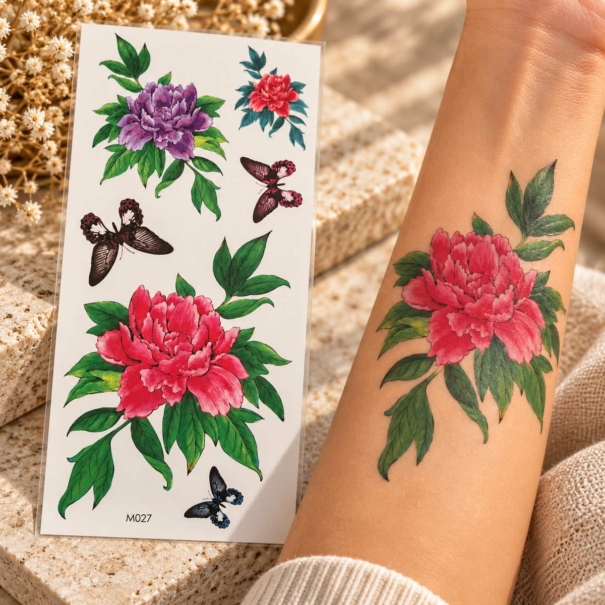 Pink and purple floral temporary tattoo sticker sheet with butterfly accents shown beside an arm