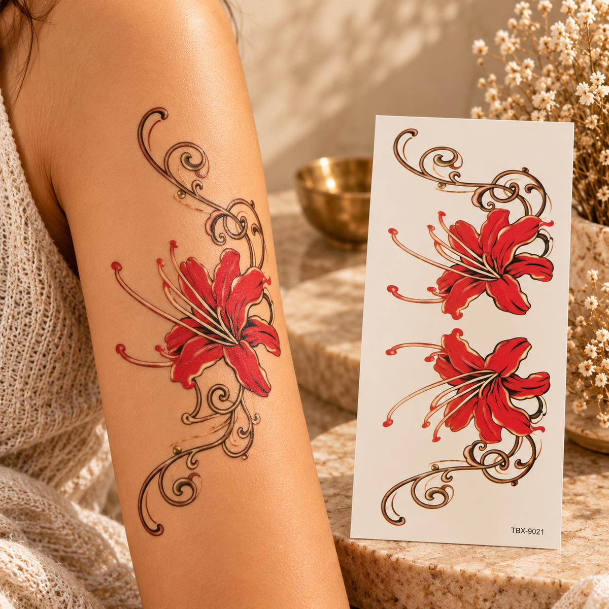Two red flowers with black-and-gold ornamental swirls on a temporary tattoo sheet, with one applied to an arm