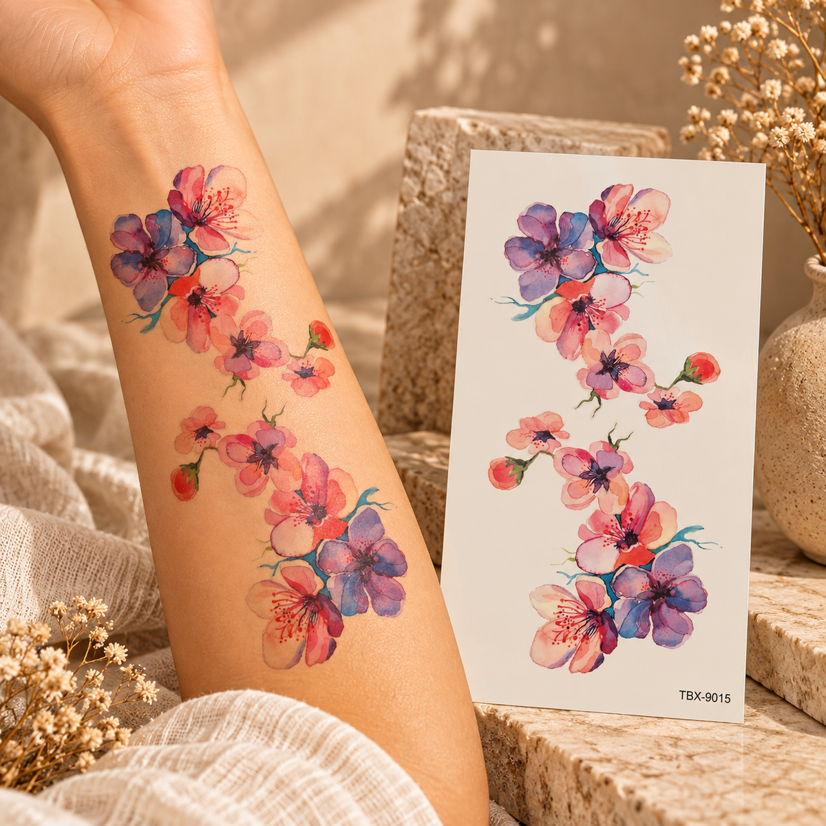 Watercolor pink, coral and purple blossom temporary tattoo flowing down an arm beside its tattoo sheet