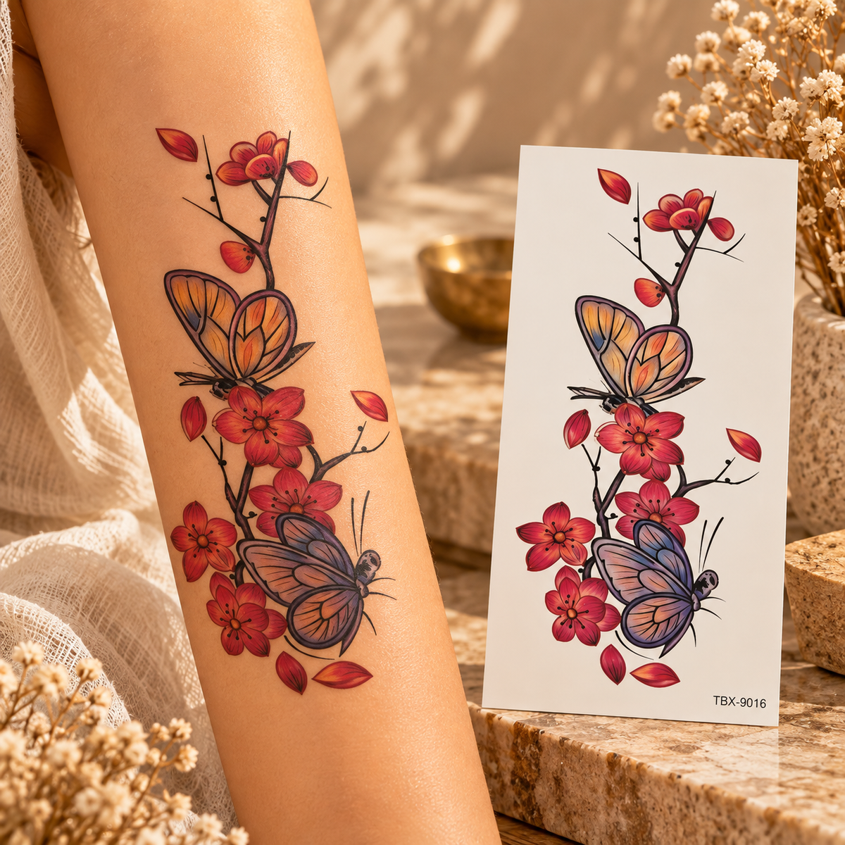 Two butterflies among red and coral blossoms on branches with falling petals, shown as a temporary tattoo on an arm and sheet