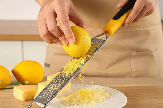 Person using a zester to grate cheese on a plate with a lemon in the background